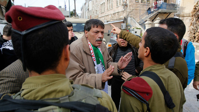 Palestinian Ziad Abu Ein (C), Head of the Anti-wall and Settlement Commission, argues with Israeli soldiers as they prevent him from crossing to Al-Shuhada Street in the West Bank city of Hebron November 29, 2014.(Reuters / Mussa Qawasma)