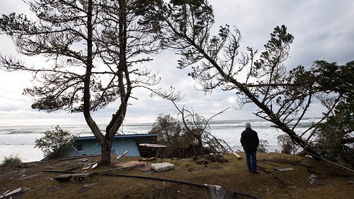 A woman watches waves roll in near a damaged house in Washaway Beach, Washington December 11, 2014 as a Pacific winter storm hits the western United States (Reuters / David Ryder)