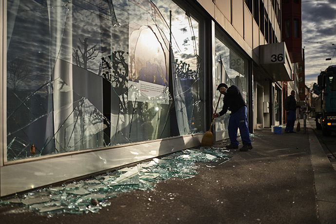 A worker cleans shattered glass outside a shop after a night of riots in Zurich on December 13, 2014. (AFP Photo/Michael Buholzer)