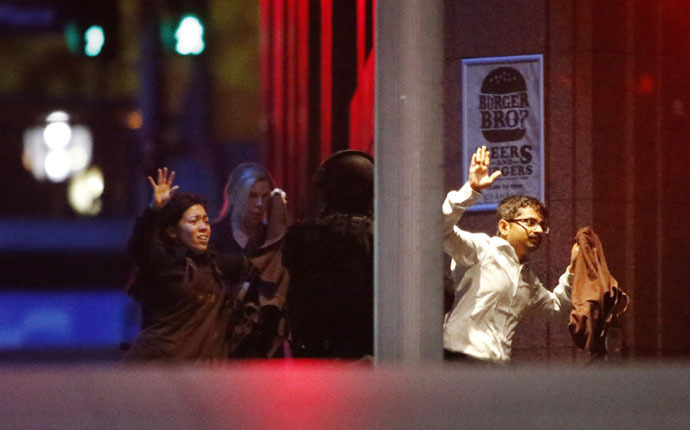 Hostages run past a police officer (C) near Lindt Cafe in Martin Place in central Sydney December 16, 2014. (Reuters/Jason Reed)