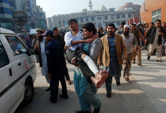 A man carries a student, who was injured during an attack by Taliban gunmen on the Army Public School, after he received treatment at a hospital in Peshawar, December 16, 2014. (Reuters/Khuram Parvez)