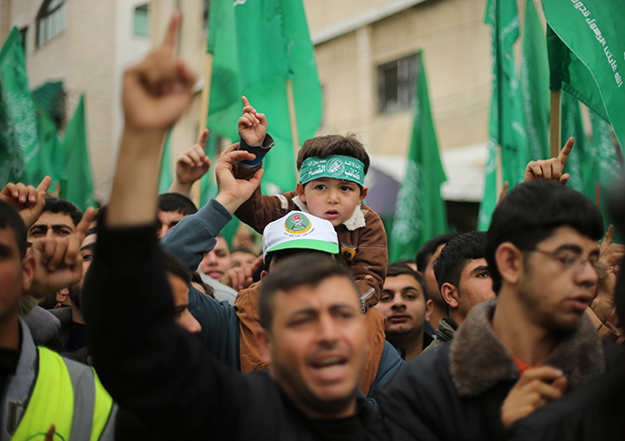A Palestinian boy wearing the headband of Hamas's armed wing sits on the shoulders of his father during a rally ahead of the 27th anniversary of Hamas founding, in Jabaliya in the northern Gaza Strip December 12, 2014 (Reuters / Mohammed Salem)