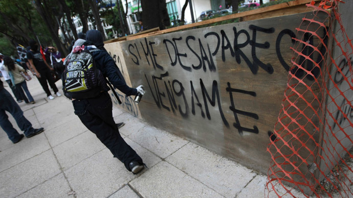 An activist sprays graffiti during a march to demand justice for the 43 missing students from Ayotzinapa Teacher Training in Mexico City December 26, 2014. (Reuters / Bernardo Montoya)