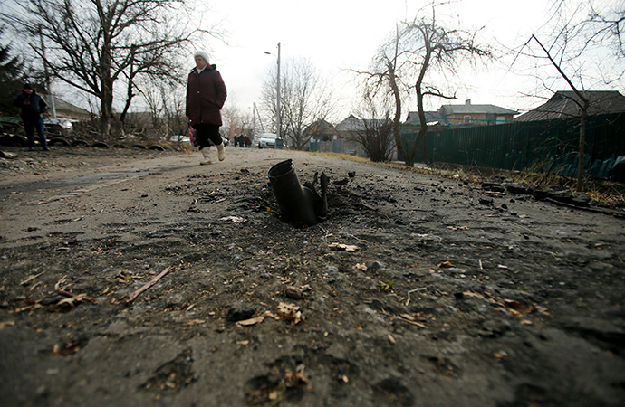A woman walks next to an exploded shell in Krasnyi Pakhar village near Donetsk, eastern Ukraine (Reuters / Antonio Bronic)