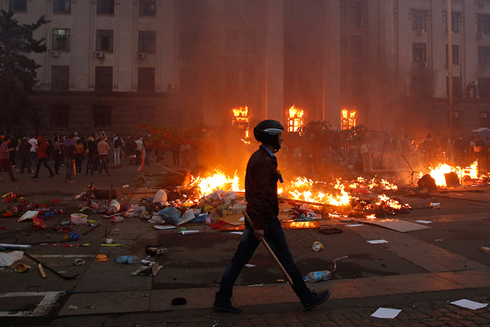 A protester walks past a burning tent camp and a fire in the trade union building in Odessa May 2, 2014. (Reuters / Yevgeny Volokin)