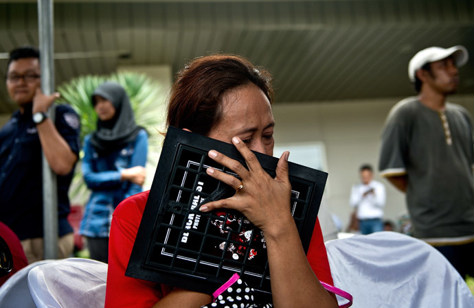 An Indonesian woman breaks down while holding a family picture of passengers onboard the missing Malaysian air carrier AirAsia flight QZ8501, outside the crisis-centre set up at Juanda International Airport in Surabaya on December 29, 2014. (AFP Photo/Manan Vatsyayana)