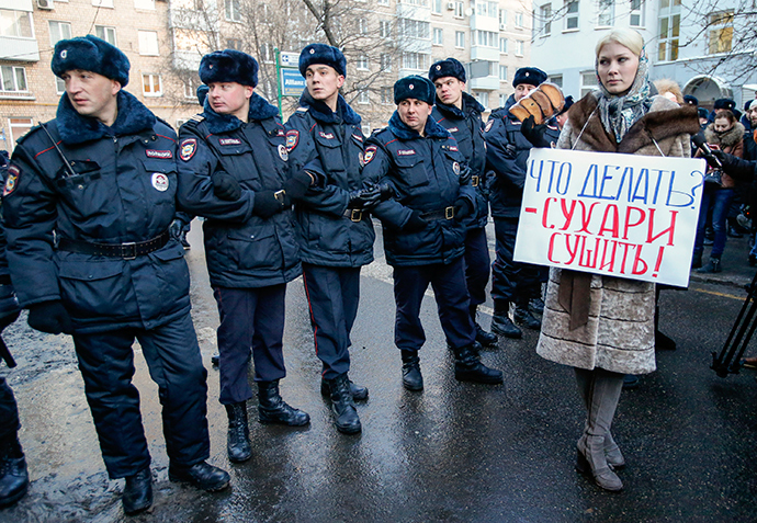 A supporter of opposition leader and anti-corruption blogger Alexey Navalny stands next to policemen blocking a street near a court building during his hearing in Moscow December 30, 2014 (Reuters / Tatyana Makeyeva)