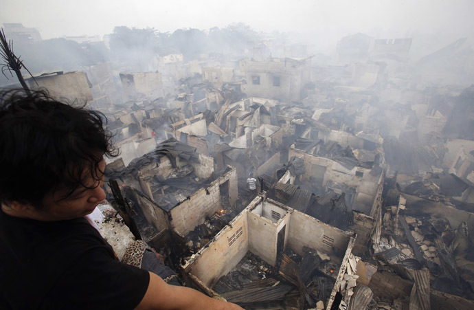 A man looks out from a veranda overlooking houses destroyed by a fire at a slum colony in Quezon city, Metro Manila January 1, 2015. (Reuters/Erik De Castro)