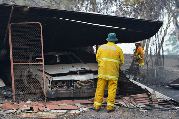 Country Fire Service volunteers work next to a burnt out shed near One Tree Hill in the Adelaide Hills, northeast of Adelaide on January 3, 2015 (AFP Photo / Brenton Edwards)