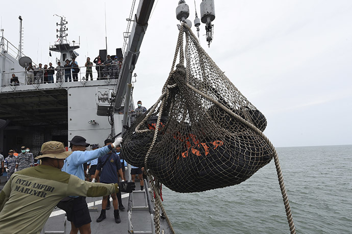 Personnel on the Indonesian Navy vessel KRI Banda Aceh lift body bags containing dead bodies recovered during a search operation for passengers of AirAsia flight QZ8501, at sea January 3, 2015. (Reuters/Adek Berry)