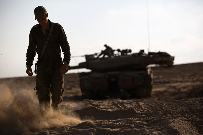 An Israeli soldier walks near his tank just outside the Israeli border with the northern Gaza Strip August 23, 2014 (Reuters / Amir Cohen)