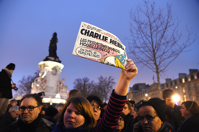 A woman holds up the satirical weekly Charlie Hebdo during a gathering at the Place de la Republique in Paris, on January 7, 2015 (AFP Photo / Dominique Faget)