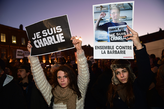 Women hold placards reading "I am Charlie" (L) and "Together against barbarism" in Toulouse on January 7, 2015 (AFP Photo / Eric Cobanis)