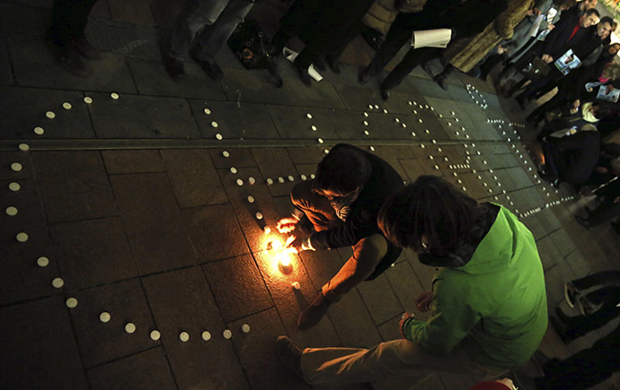 People try to light candles to form the word "Charlie" to pay tribute to the victims of a shooting by gunmen at the offices of weekly satirical magazine Charlie Hebdo in Paris, in front of the European Parliament in Brussels January 7, 2015. (Reuters/Francois Lenoir)