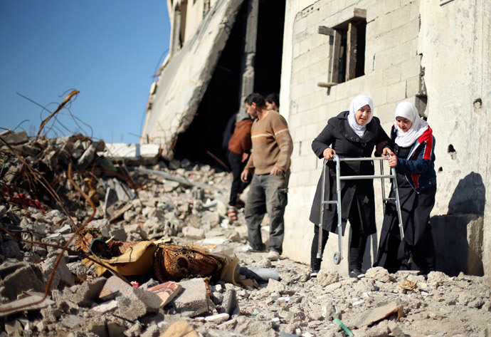 Palestinian girl Manar Al-Shinbari (2nd R), 15, who lost both her legs in what medics said was Israeli shelling at a UN-run school where she was taking refuge during the 50-day war last summer, uses her walker at the ruins of her house that witnesses said was destroyed by Israeli shelling during the war, in Biet Hanoun in the northern Gaza Strip January 13, 2015. (Reuters / Mohammed Salem)