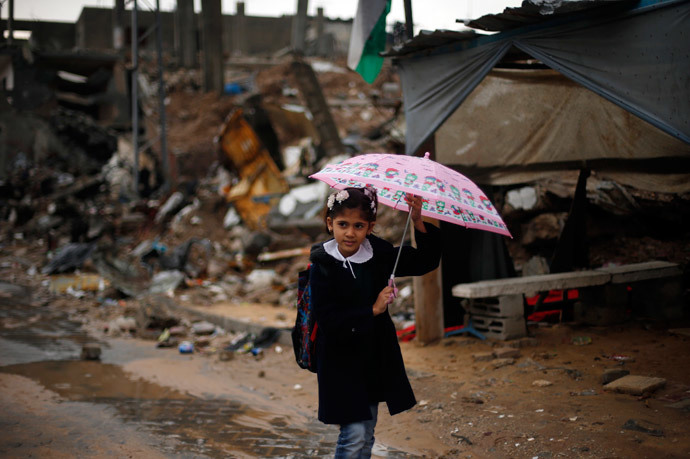 A Palestinian school girl holds an umbrella as she walks near the ruins of houses that witnesses said were destroyed by Israeli shelling during the most recent conflict between Israel and Hamas (Reuters / Suhaib Salem)