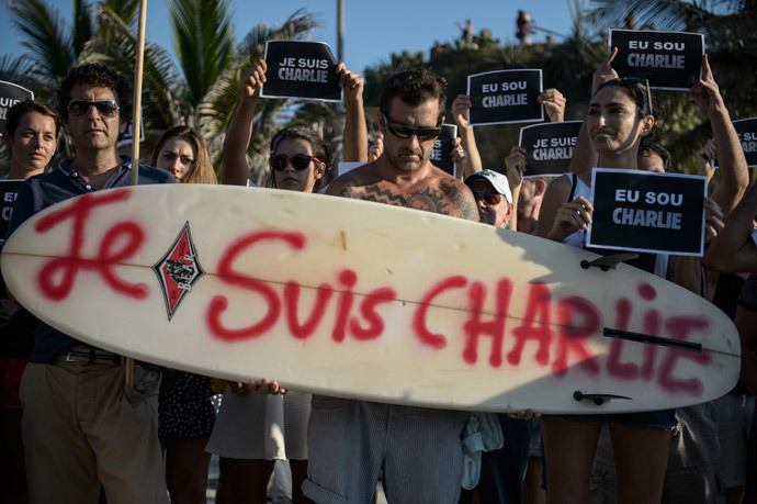 A man holds a surfboard reading "I am CHARLIE" during a rally at Arpoador beach in Rio de Janeiro, Brazil on January 11, 2015 in tribute to the 17 victims of this week's Islamist attacks in France (AFP Photo / Yasuyoshi Chiba)