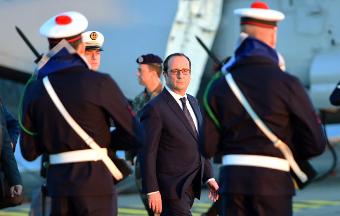 French President Francois Hollande reviews the troops during his visit on the French nuclear aircraft carrier Charles de Gaulle to present his New Year wishes to the French military forces, on January 14, 2015 off the coast of Toulon, southern France. (AFP Photo / Pool / Anne-Christine Poujoulat)