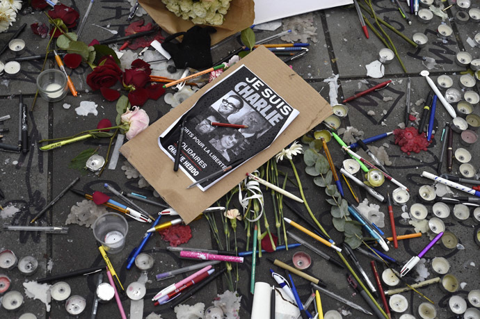 Pens and pencils are placed on the ground near a sign with the portraits of late Charlie Hebdo editor Stephane Charbonnier (aka Charb), late French cartoonists Georges Wolinski, Bernard Verlhac (aka Tignous) and Jean Cabut (aka Cabu) on the Place de la Republique (Republic Square) in Paris on January 8, 2015. (AFP Photo/Martin Bureau)