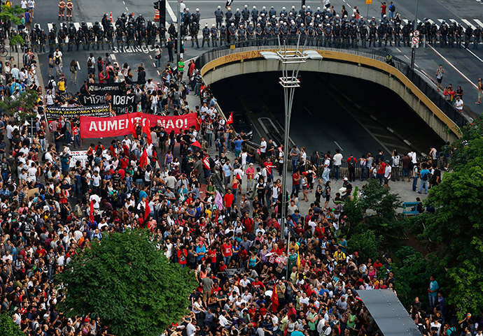 Demonstrators march in front of a line of riot police during a protest against fare hikes for city buses, subway and trains in Sao Paulo January 16, 2015 (Reuters / Nacho Doce)