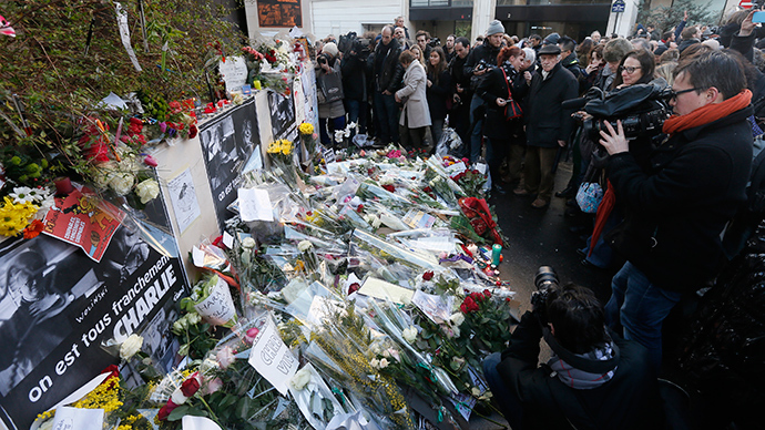 Journalists and citizens surround flowers placed in front of the offices of weekly satirical newspaper Charlie Hebdo in Paris (Reuters / Gonzalo Fuentes)