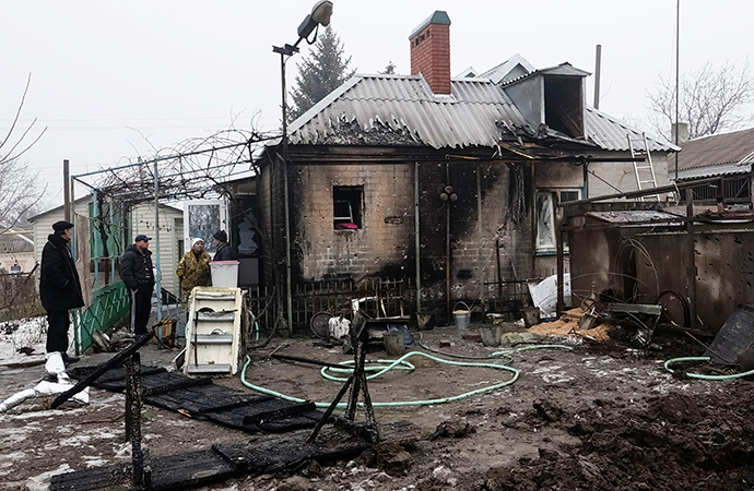 Local residents inspect their home, which was damaged by shelling in the village of Sartan, near Mariupol (Reuters / Nikolay Ryabchenko)