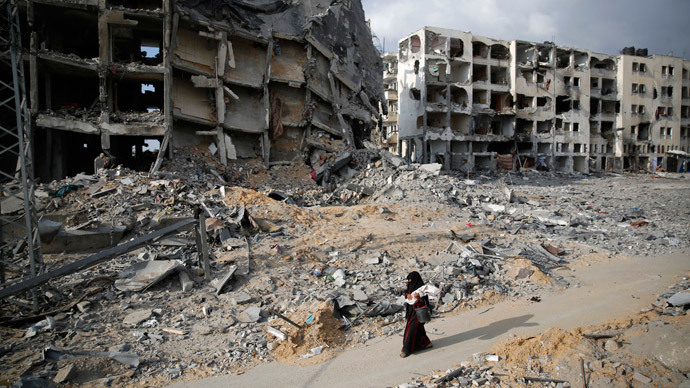 A Palestinian woman walks past buildings destroyed by what police said were Israeli air strikes and shelling in the town of Beit Lahiya in the northern Gaza Strip August 3, 2014.(Reuters / Finbarr O'Reilly)