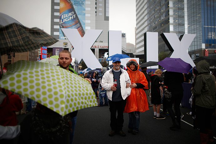 Football fans pose in the pouring rain in front of an NFL Super Bowl XLIX sign in downtown Phoenix, Arizona January 30, 2015 (Reuters / Lucy Nicholson)