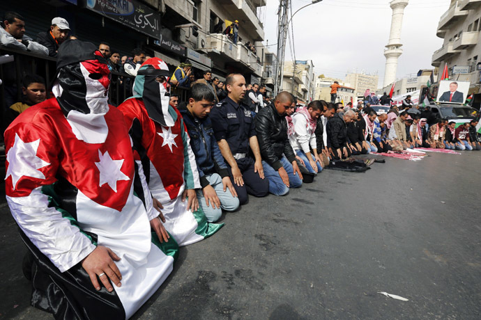 Protesters dressed in Jordanian flag perform Friday prayers along a street outside al-Husainy mosque before a march in downtown Amman February 6, 2015. (Reuters/Muhammad Hamed)