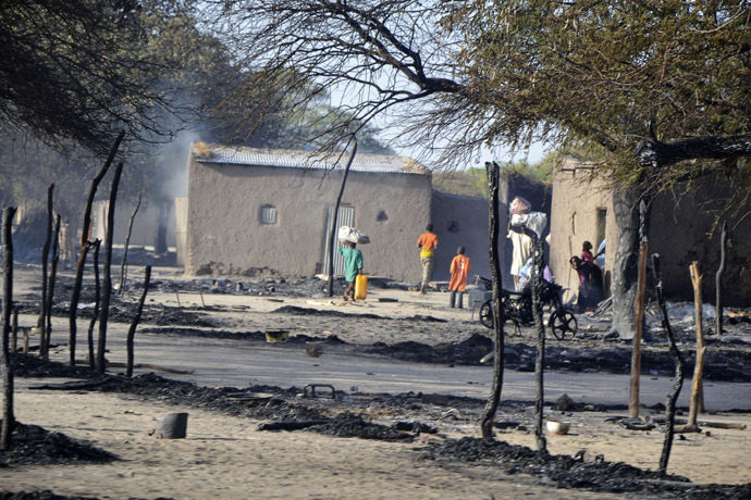 People walk in a burnt compound after an attack by Boko Haram militants in the village of Ngouboua February 13, 2015. (Reuters/Madjiasra Nako)