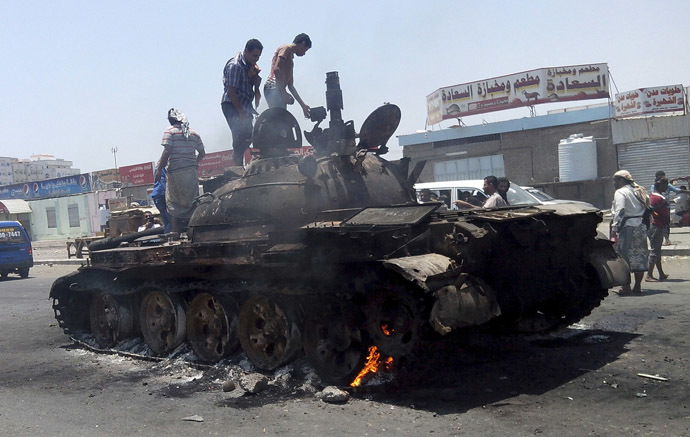 People stand on a tank that was burnt during clashes on a street in Yemen's southern port city of Aden March 29, 2015. (Reuters/Stringer)