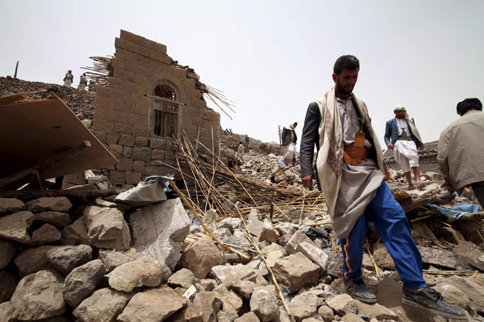People stand on the rubble of houses destroyed by an air strike in the Okash village near Sanaa April 4, 2015. (Reuters/Mohamed al-Sayaghi)
