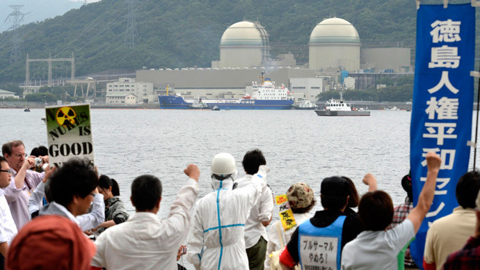 Protesters raise their fists at a freighter (C), carrying plutonium-uranium mixed oxide (MOX) fuel processed in France, as it arrives at Kansai Electric Power Co.'s Takahama nuclear power plant in Takahama town, Fukui prefecture, in this photo taken by Kyodo June 27, 2013.(Reuters / Kyodo)