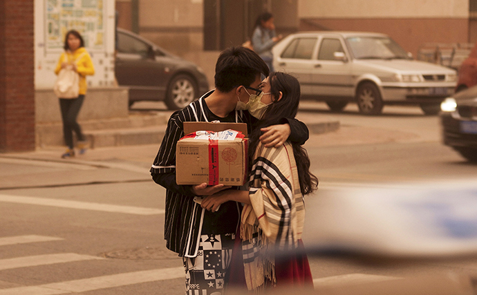 A couple wearing masks kiss along a street during a sandstorm in Beijing, April 15, 2015 (Reuters / China Daily)