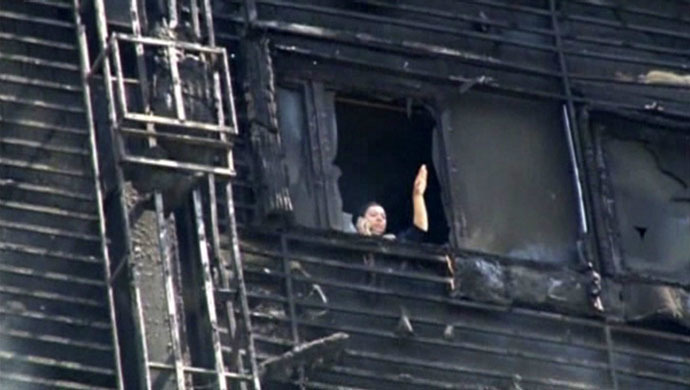 A woman tries to get the attention of emergency workers inside a multi-storey residential building on fire in Baku, Azerbaijan, in this still image taken from video shot on May 19, 2015. (Reuters/Reuters TV)
