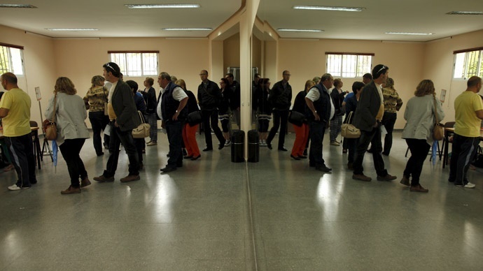 People are reflected in a mirror (R) as they wait in line to cast their ballots at a polling station during municipal elections in Ronda, southern Spain May 24, 2015.(Reuters / Jon Nazca)