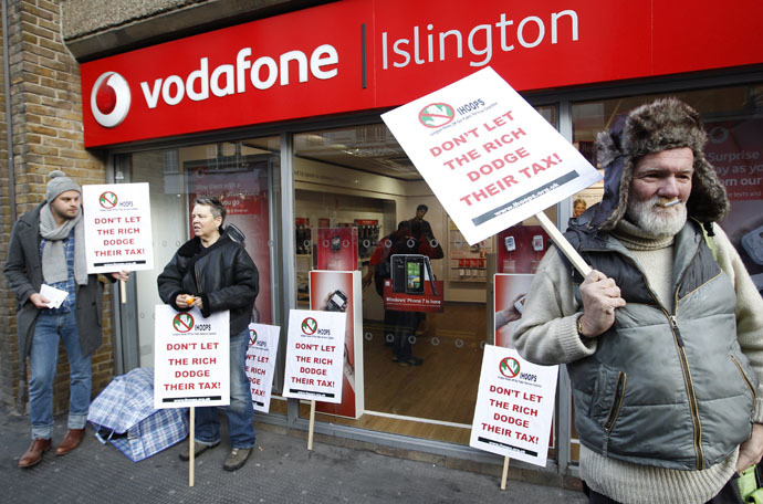 Demonstrators stand poutside a branch of Vodafone as they protest against the company not paying enough tax, in north London, December 11, 2010. (Reuters/Andrew Winning)
