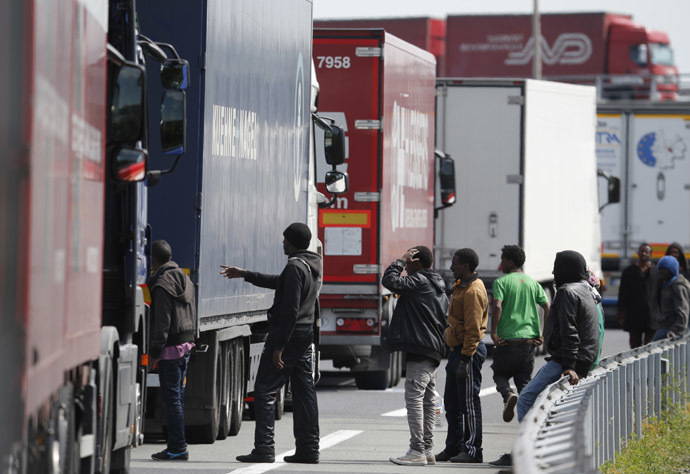 A group of migrants gather near a line of lorries waiting on the motorway which leads to the Channel Tunnel terminal in Calais, northern France, June 24, 2015. (Reuters / Christian Hartmann)