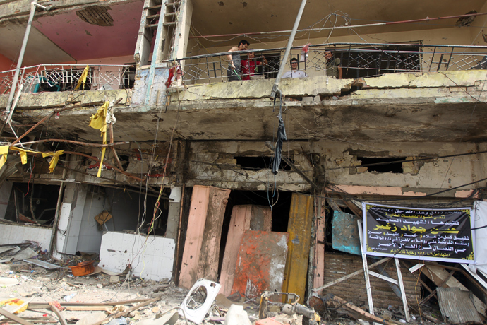 Iraqi stand on the balcony of a damaged building the day after twin car bombs in the Karrada area of the capital Baghdad on August 1, 2012 (AFP Photo / Ahmad Al-Rubaye) 