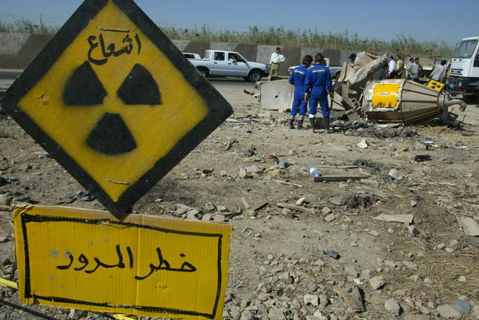 Greenpeace activists stand in front of a uranium oxide mixing vat outside the grounds of the Tuwaitha nuclear facility, 30 kms south of Baghdad, where it was allegedly dumped after being stolen by looters 24 June 2003 (AFP Photo / Cris Bouroncle)