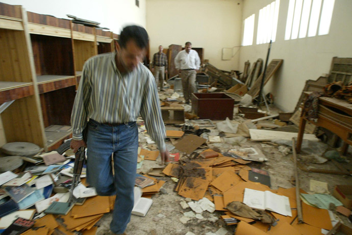 Iraqi guards walk in the ransacked and looted Iraq's largest archeological museum in Baghdad, 13 April 2003. (AFP Photo)