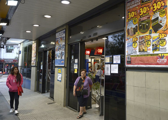 A woman leaves a supermarket with a promotional poster outside in Buenos Aires (AFP Photo / Juan Mabromata)