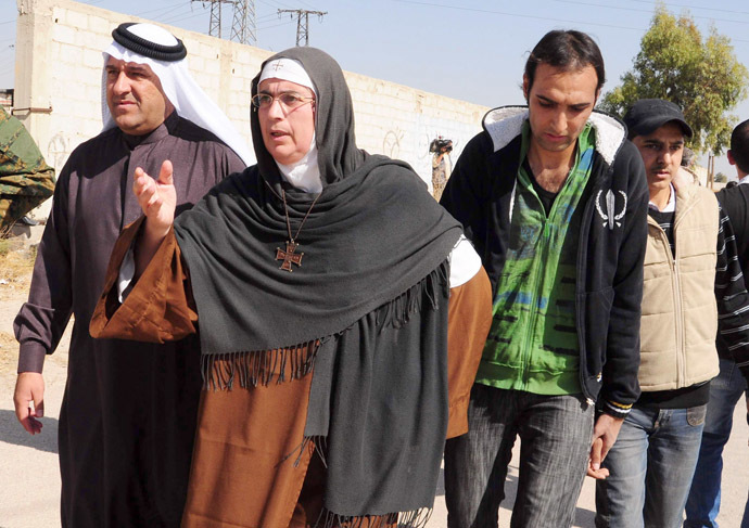 Mother Agnes-Marie de la Croix and the Red Cresent (unseen) with the help of the Social Affairs Ministry, lead the evacuation of Syrian civilians from the war-battered suburb of Damascus, Moadamiyet al-Sham, as fighting between pro-government troops and rebel fighters continues in districts of the capital, on October 29, 2013. (AFP Photo)