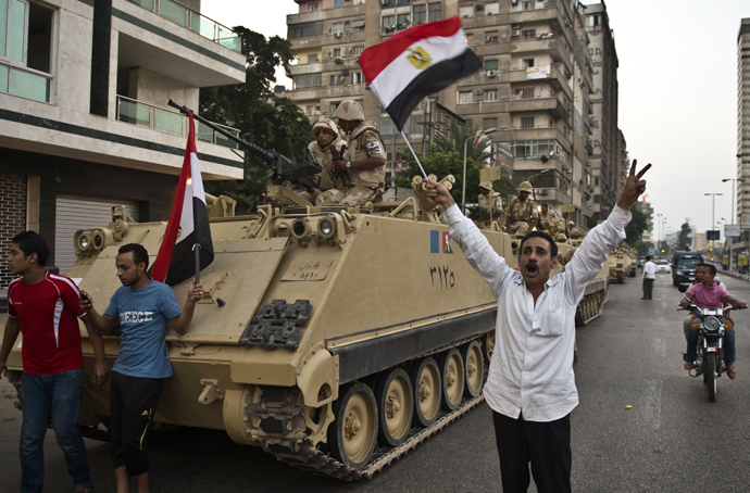 Egyptians salute Army tanks upon their deployment on a street leading to Cairo University on July 3, 2013 (AFP Photo / Khaled Desouki)