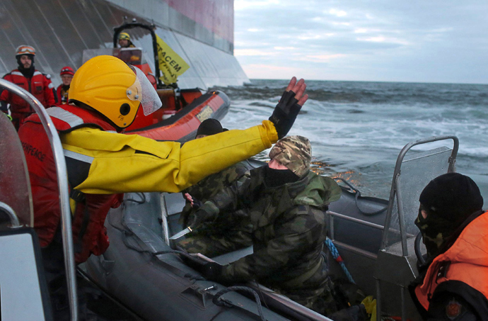 A handout photo taken by Greenpeace on September 18, 2013, shows a camouflage clad mask wearing officer of Russian Coast Guard (C) pointing a knife at a Greenpeace International activist (L) during an environmentalists' attempt to climb Gazpromâs âPrirazlomnayaâ Arctic oil platform somewhere off Russia north-eastern coast in the Pechora Sea. (AFP Photo / Greenpeace / DenisSINYAKOV)