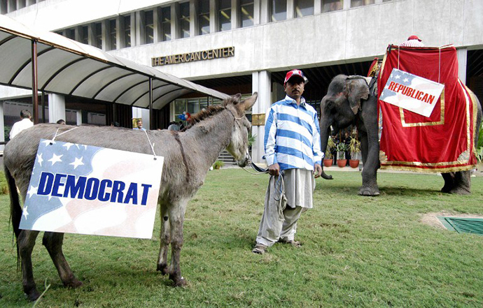 An Indian man stands between a donkey bearing a Democrats banner and an elephant bearing a Republicans banner during an election watch organised at the American Centre in New Delhi (AFP Photo / Prakash Singh)