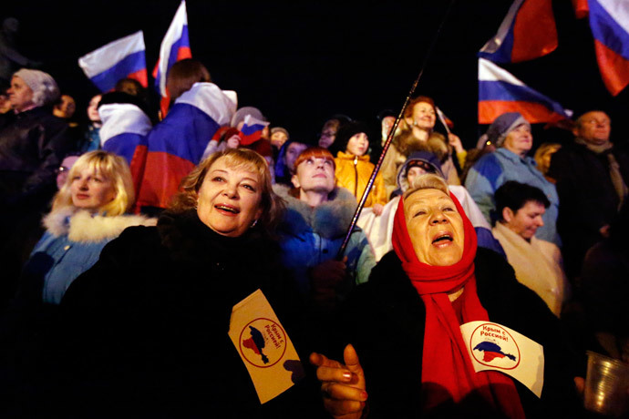 Two women hold flags reading "Crimea is with Russia" as people wait for the announcement of preliminary results of today's referendum on Lenin Square in the Crimean capital of Simferopol March 16, 2014.(Reuters / Thomas Peter)