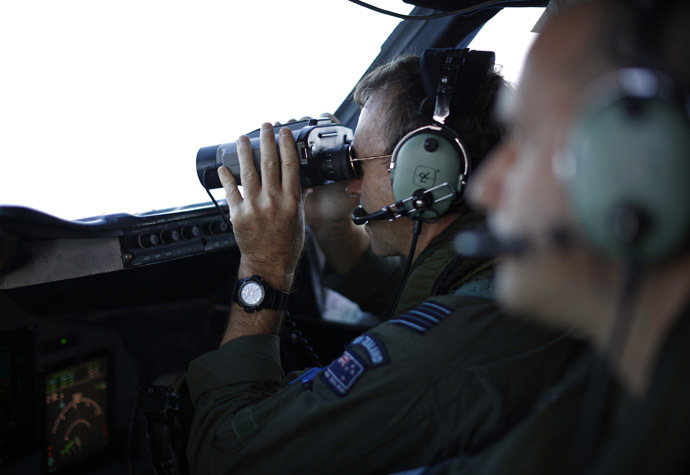 Wing Commander Rob Shearer looks through binoculars on the flight deck of a Royal New Zealand Air Force P-3K2 Orion aircraft during a search for the missing Malaysian Airlines flight MH370 over the southern Indian Ocean, March 29, 2014. (Reuters)