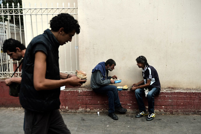 People eat after they received food donated by the Greek church in central Athens (AFP Photo)