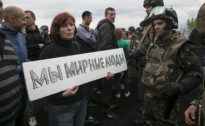 A civilian holds a sign in front of Ukrainian troops at a checkpoint near the town of Slaviansk in eastern Ukraine May 2, 2014. The sign reads, "We are peaceful people." (Reuters / Baz Ratner)